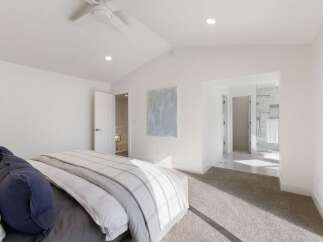Experience modern luxury in this spacious bedroom featuring a vaulted ceiling and a sleek ceiling fan.