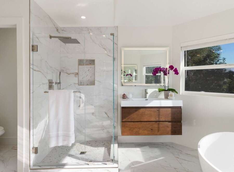 Experience modern luxury in this stunning bathroom, featuring a spacious glass-enclosed shower with marble tile and a rainfall showerhead.