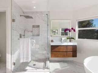 Experience modern luxury in this stunning bathroom, featuring a spacious glass-enclosed shower with marble tile and a rainfall showerhead.