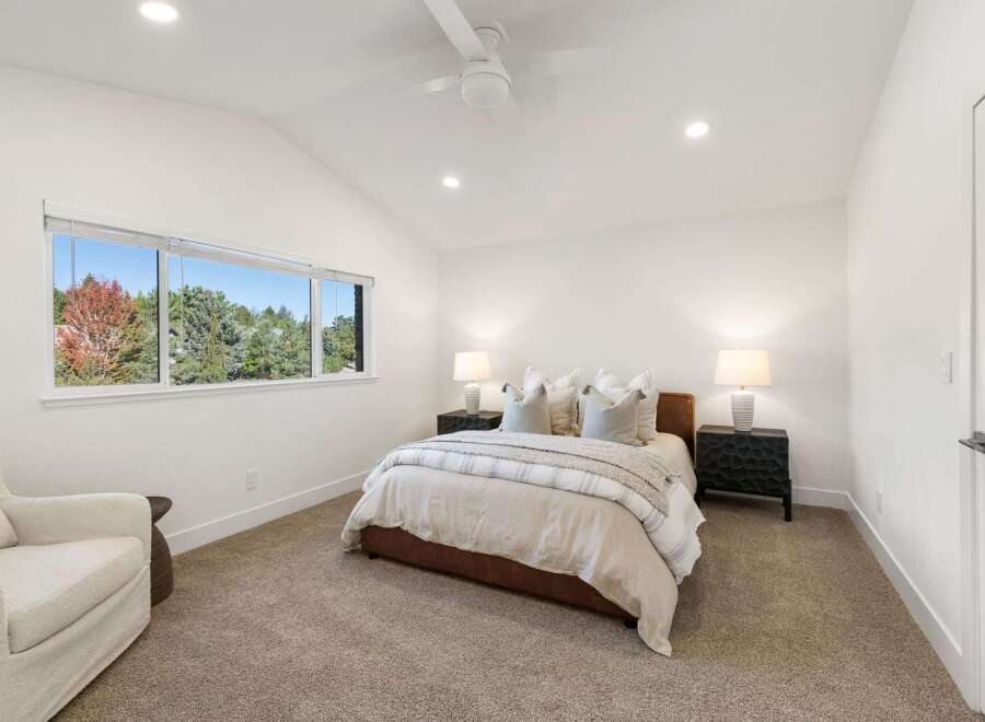 Experience serene living in this beautifully appointed bedroom, featuring a plush bed with elegant linens and two matching nightstands with lamps.