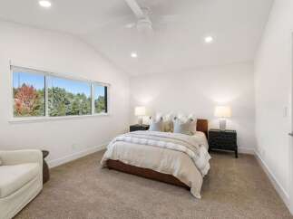 Experience serene living in this beautifully appointed bedroom, featuring a plush bed with elegant linens and two matching nightstands with lamps.