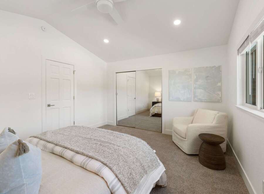 This bright and airy bedroom features a vaulted ceiling with a modern ceiling fan and recessed lighting.