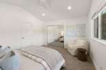 This bright and airy bedroom features a vaulted ceiling with a modern ceiling fan and recessed lighting.