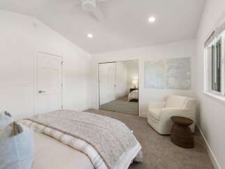 This bright and airy bedroom features a vaulted ceiling with a modern ceiling fan and recessed lighting.