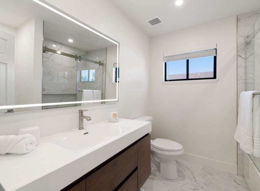 Experience modern luxury in this beautifully appointed bathroom, featuring a sleek vanity with a vessel sink and a stunning illuminated mirror.