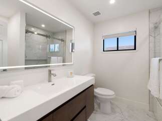 Experience modern luxury in this beautifully appointed bathroom, featuring a sleek vanity with a vessel sink and a stunning illuminated mirror.
