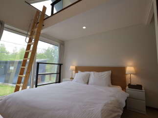 Experience modern living in this stylish bedroom featuring a comfortable queen-sized bed with crisp white linens and a sleek wooden headboard.