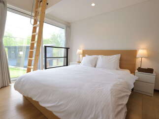 Experience modern comfort in this serene bedroom featuring a plush king-sized bed dressed in crisp white linens.