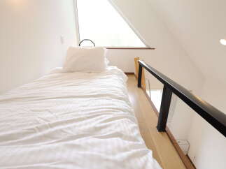 Discover this charming loft bedroom featuring a comfortable single bed with crisp white linens, perfect for a cozy retreat.