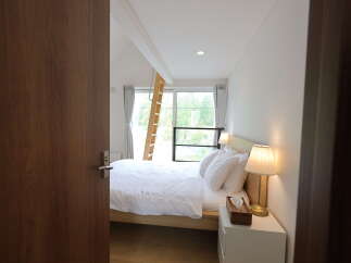 Step into this inviting bedroom, featuring a comfortable bed dressed in crisp white linens and a charming bedside lamp casting a warm glow.