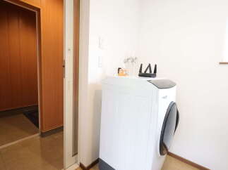 Discover a modern laundry space featuring a sleek white washing machine equipped with a front-loading door and a top control panel.