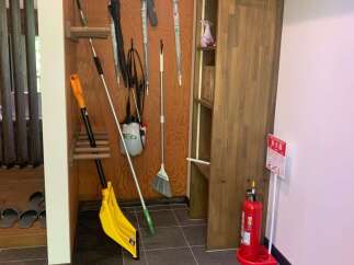 Discover practical storage solutions in this entryway, featuring a dedicated rack for umbrellas and cleaning tools like brooms and dustpans.
