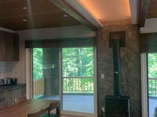 Experience cozy living in this charming home featuring a rustic stone fireplace and a modern wood-burning stove, perfect for gathering on cool evenings.
