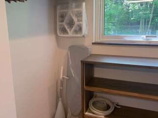Discover convenient storage solutions in this versatile space, featuring a built-in closet rod, a wall-mounted organizer, and a compact ironing board.