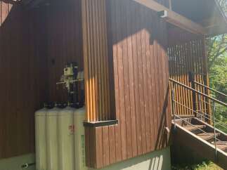 Discover this charming property featuring a rustic wooden exterior and a convenient covered area housing gas tanks.