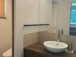 This modern bathroom features a sleek vanity with a vessel sink and a chrome faucet, complemented by a large mirror with integrated lighting.