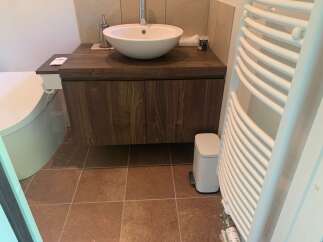 This modern bathroom features a sleek vanity with a vessel sink and a wall-mounted faucet.