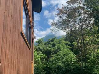 Experience serene living in this charming wooden cabin, nestled amidst lush greenery and offering breathtaking mountain views.