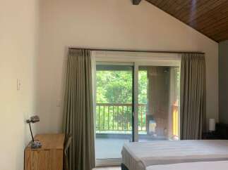 Experience serene living in this charming room featuring two comfortable beds and a dedicated workspace with a wooden desk and chair.