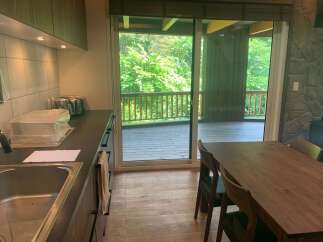 Enjoy seamless indoor-outdoor living with this stunning property featuring a modern kitchen and a spacious dining area that opens onto a large wooden deck.