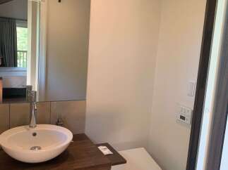 This modern bathroom features a sleek vessel sink atop a rich wooden vanity, complemented by a stylish chrome faucet.