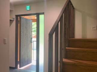 Step into this inviting entryway featuring a modern wooden staircase and a welcoming open door leading to the outdoors.