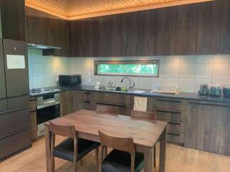 Experience modern living in this beautifully appointed kitchen, featuring sleek dark wood cabinetry and a spacious wooden dining table perfect for family meals.