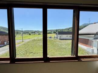Enjoy breathtaking views from this charming property, featuring a spacious window overlooking a lush green meadow dotted with wildflowers.