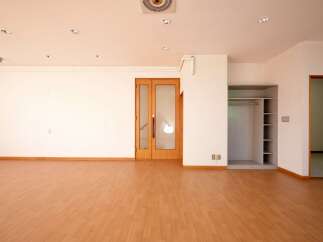 Discover this spacious and bright room featuring a polished wooden floor and ample natural light.