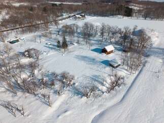 Escape to a serene winter wonderland with this charming log cabin nestled in a snow-covered landscape.