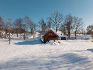 Escape to a winter wonderland with this charming wooden cabin nestled in a serene, snow-covered landscape.