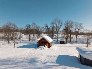 Escape to a winter wonderland with this charming wooden cabin nestled in a serene, snow-covered landscape.