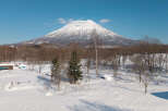 Experience the serene beauty of a snow-covered landscape with a majestic, snow-capped mountain as the backdrop.