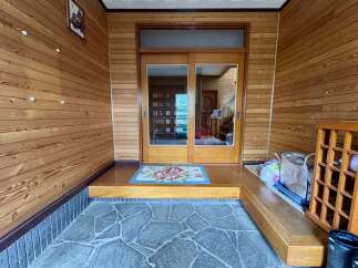 Step into this charming entryway featuring warm wooden paneling and a welcoming floral mat.