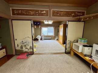 Discover traditional Japanese living with this charming room featuring elegant shoji screens and intricate wood carvings adorning the walls.