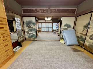 Step into a serene Japanese-style room featuring traditional shoji screens and elegant pine tree artwork.