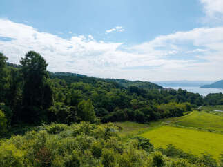Discover this stunning property offering breathtaking panoramic views of a serene lake and lush green hills.