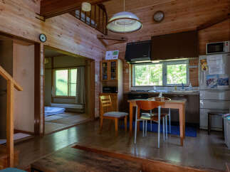Experience rustic charm in this cozy wooden cabin, featuring a functional kitchen area with a microwave and refrigerator, and a separate tatami room perfect for relaxation.