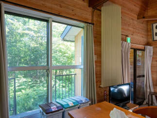Enjoy the serene natural views from this room, featuring large windows that open to a lush green forest.