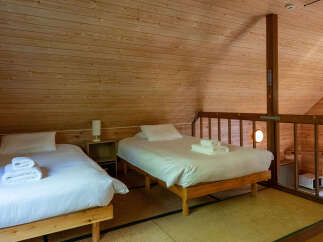 Experience cozy comfort in this charming loft bedroom, featuring two inviting beds with crisp white linens and plush towels.