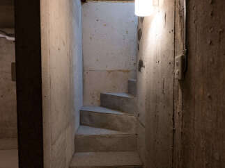 Discover the raw potential of this unfinished basement, featuring a sturdy concrete staircase leading to further possibilities.
