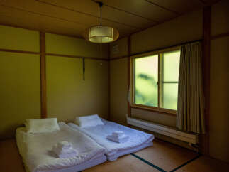 Experience serene Japanese living in this tranquil room featuring two comfortable futon beds laid out on traditional tatami flooring.
