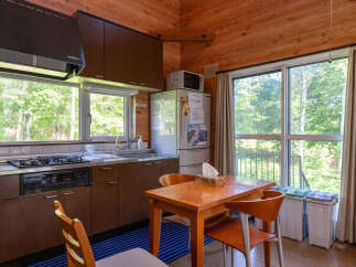 Experience cozy living in this charming kitchen featuring warm wood paneling and abundant natural light from large windows overlooking lush greenery.