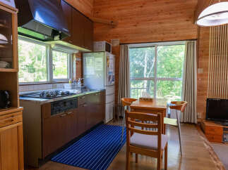 Experience cozy living in this charming kitchen and dining area, featuring warm wooden walls and ample natural light from large windows.