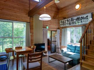 Experience rustic charm in this cozy cabin featuring a spacious living area with a comfortable blue sofa and a wooden coffee table.