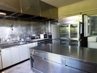 This spacious commercial kitchen features a large stainless steel island, perfect for food preparation and service.