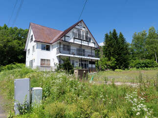 Discover this charming white house nestled amidst lush greenery and blooming wildflowers.