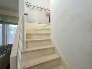 Ascend to the upper level via this charming staircase, featuring light wood treads and a soft, neutral riser color that complements the textured walls.