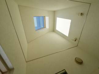 Discover this unique interior space featuring a striking geometric design with a large window offering natural light.