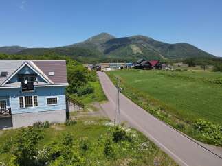 Discover this charming blue house nestled in a serene rural landscape, offering breathtaking views of a majestic mountain.
